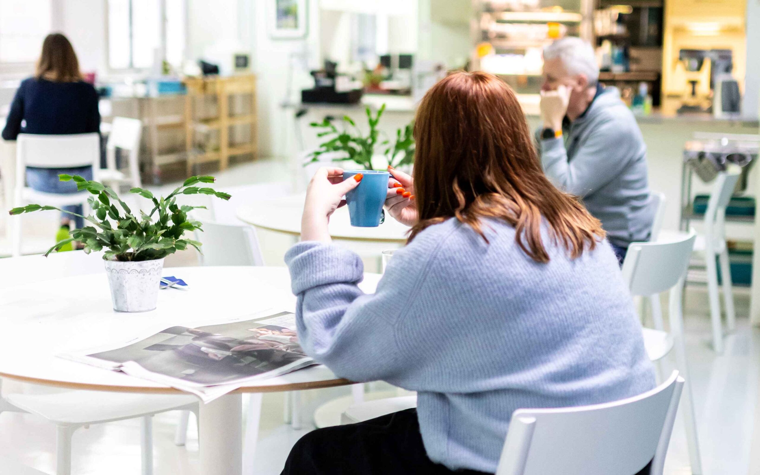 Kolme henkilöä istuu kahvilatilassa